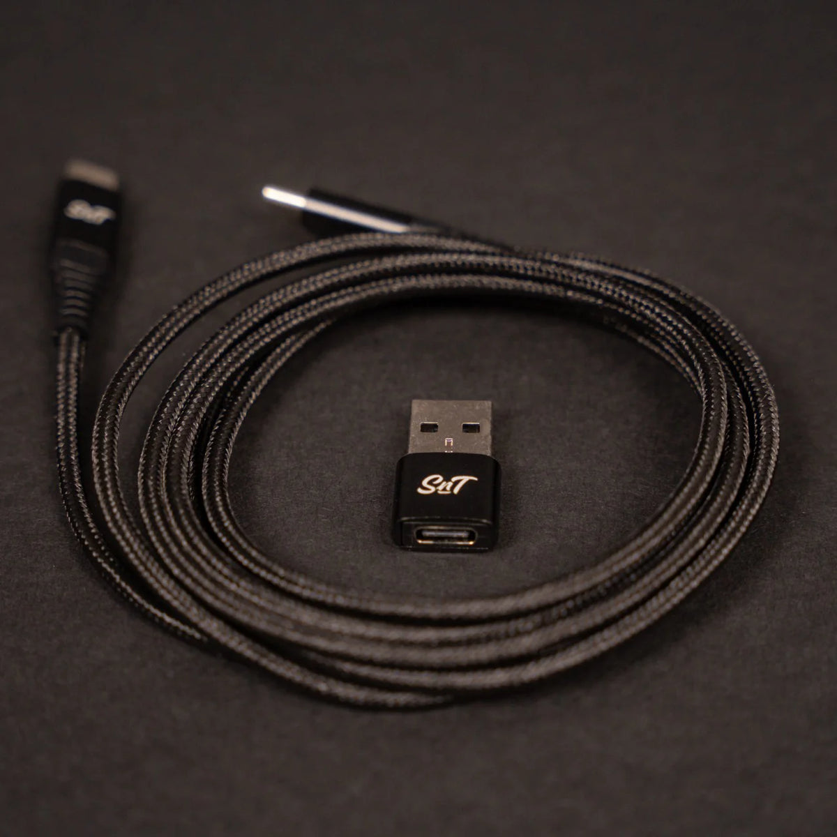 Sim'n Tonic Nome II MIDI interface with rolled USB cable and adapter, showcasing the compact design and connectivity options.
